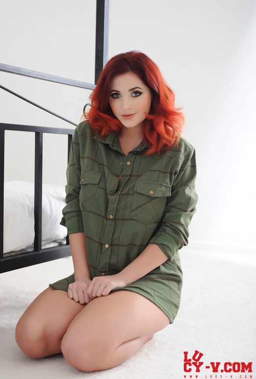 Lucy V teasing on the bed in her green shirt